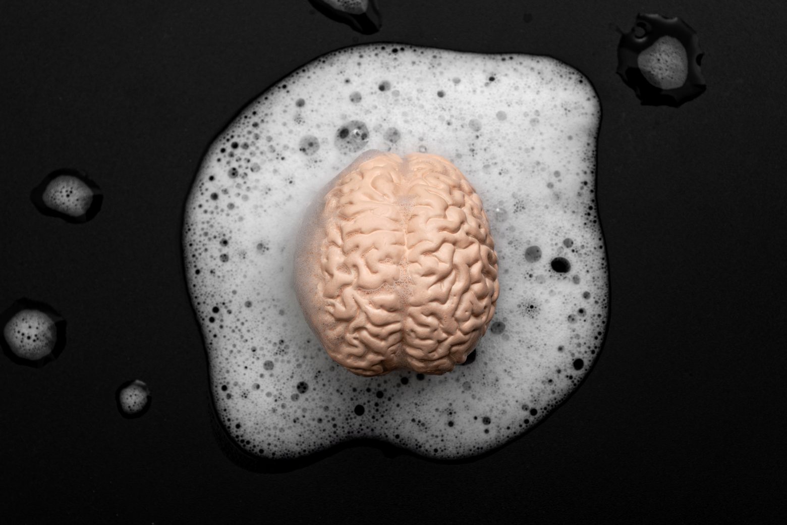 Hjärntvätt, lägre kritiskt tänkande och tankekontroll koncept med mänsklig hjärntvätt i tvålbubblor isolerad på svart bakgrund